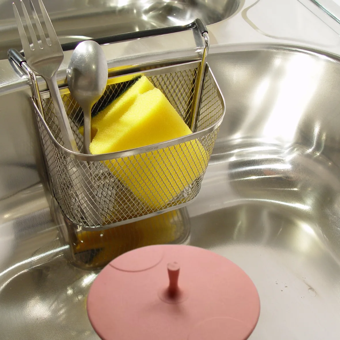 Tapón universal autoadherente DF rosa junto a un canasto de cocina